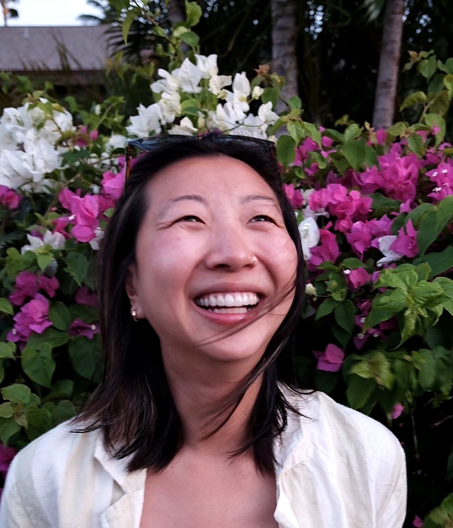 Samantha Fu, laughing outdoors in front of bougainvillea flowers